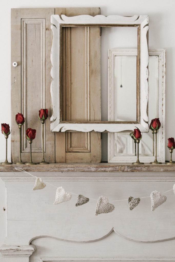 layering vintage mirrors and frames on mantle valentine's day mantel with red roses Valentine's Day Mantel
