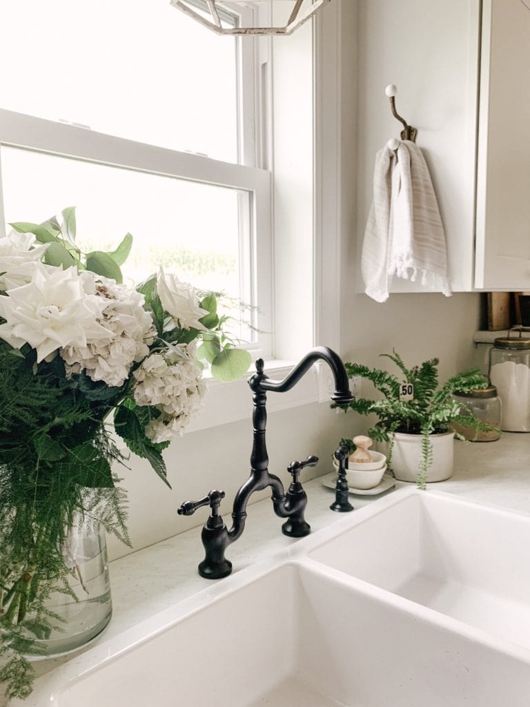 https://sarahjaneinteriors.blog/wp-content/uploads/2019/08/black-faucet-white-double-farmhouse-sink-with-hydrangeas-768x1024.jpeg