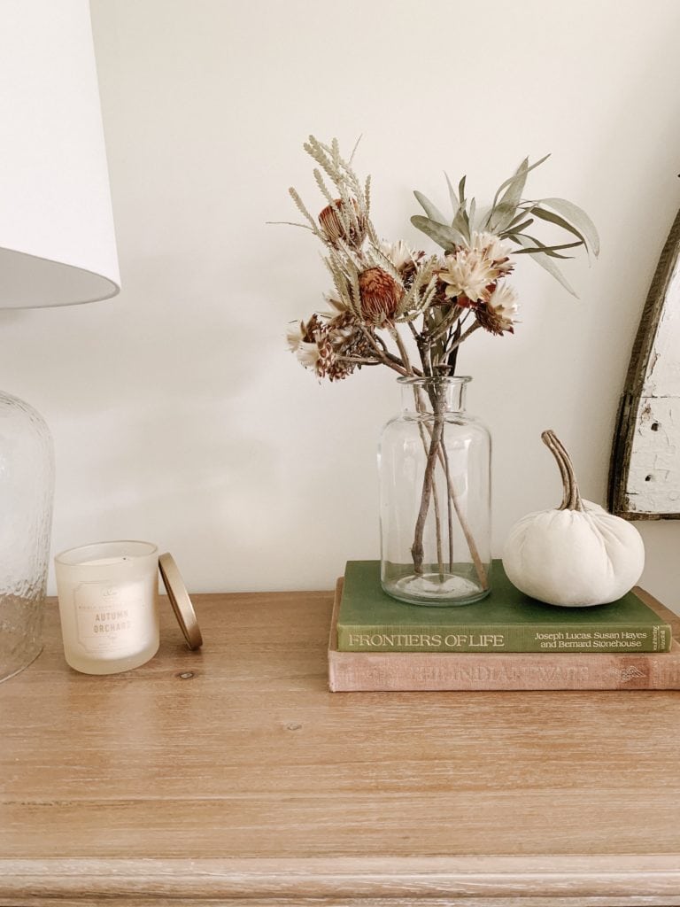 using books faux pumpkin candle and dried florals in bedroom fall decor