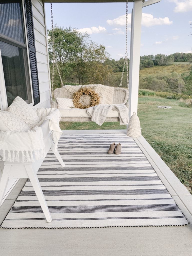 porch swing with striped outdoor area rug on wrap around porch
