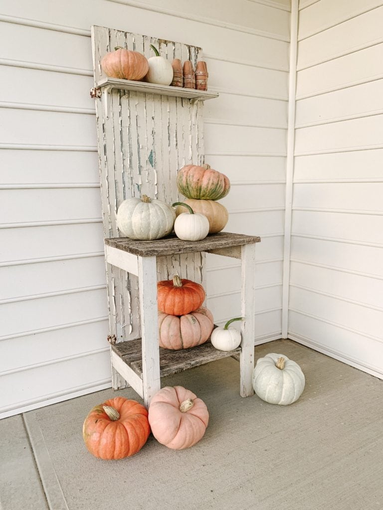 fun colored pumpkins displayed on a potting bench on porch