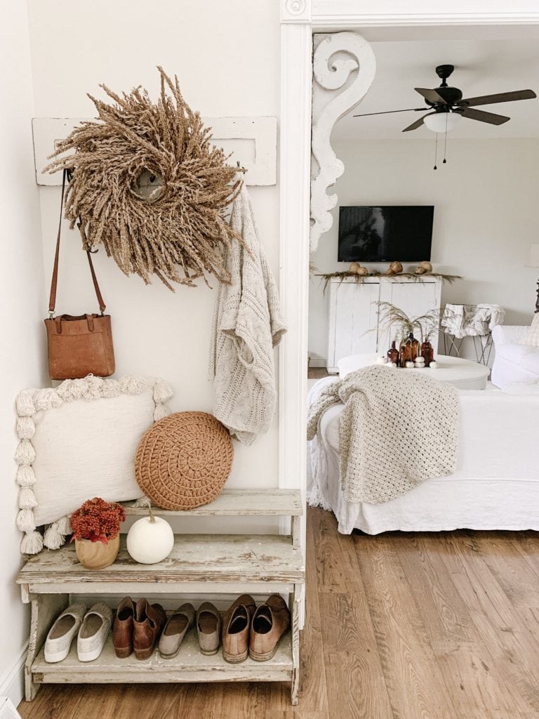 cozy autumn entryway styled with wheat wreath sweater shoes orange pillow
