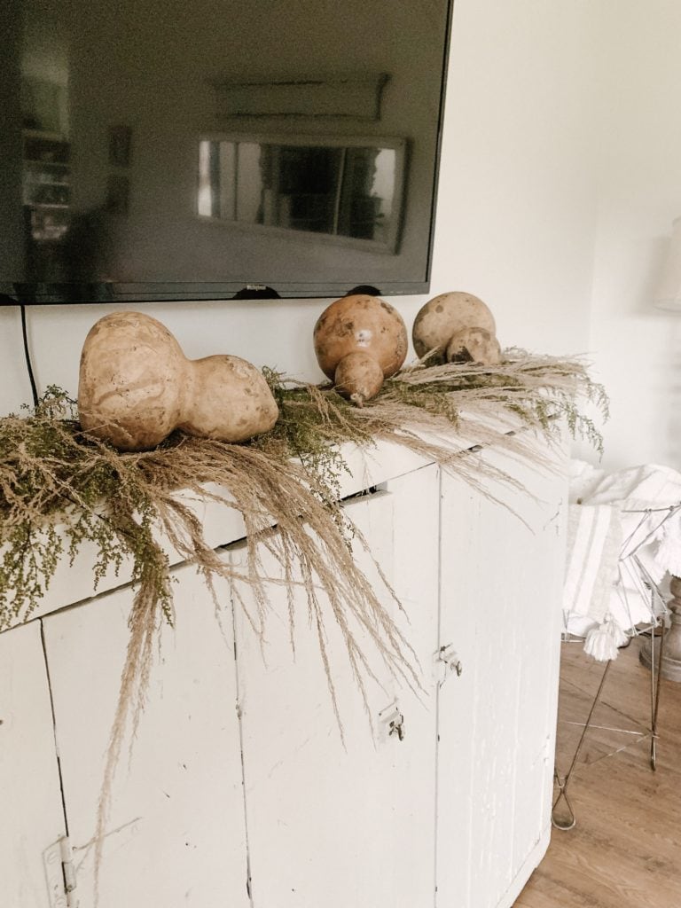 sweet annie pampas grass and large dried gourds on antique white cabinet