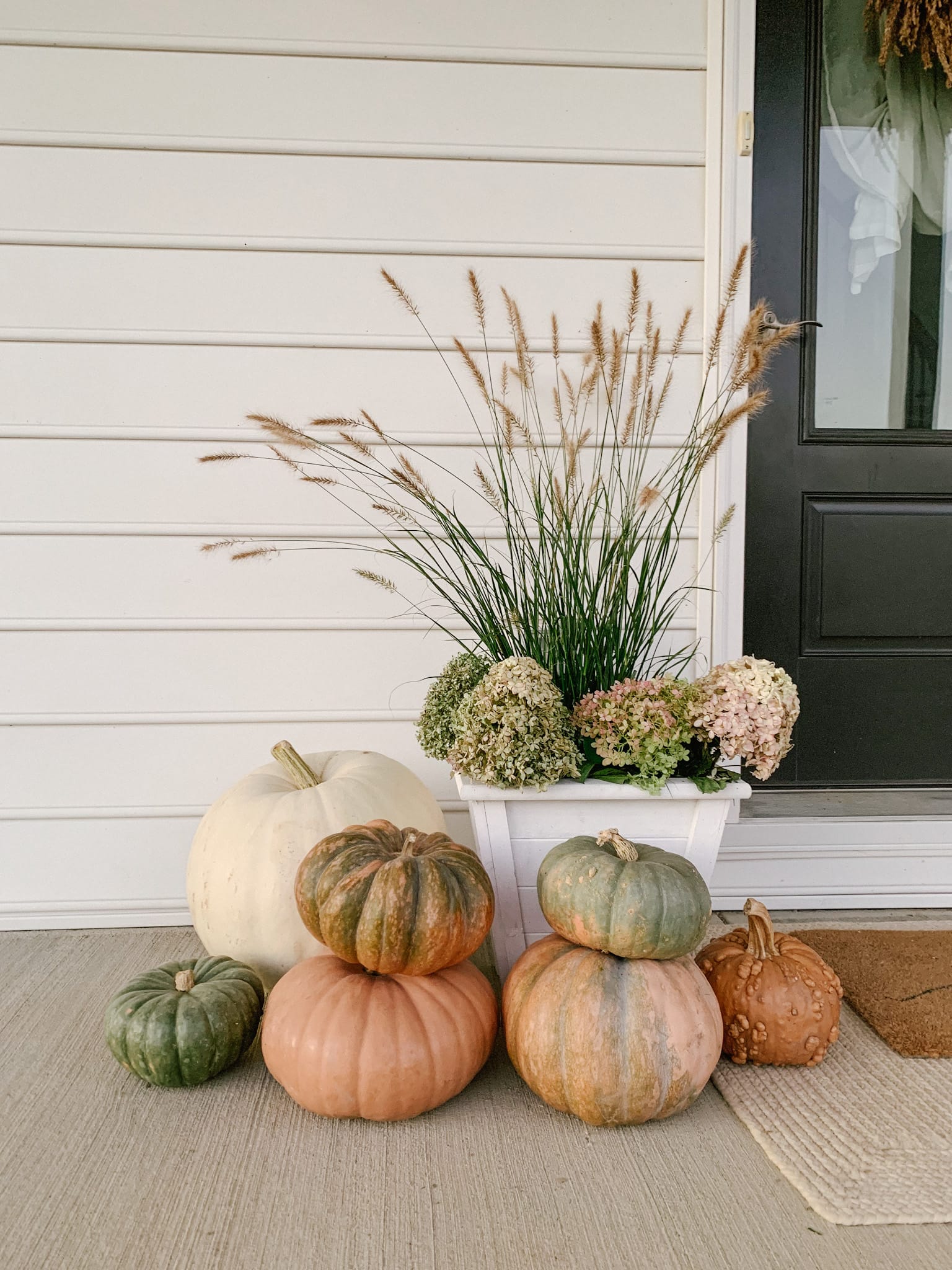 muted orange green and white pumpkins on farmhouse fall front porch